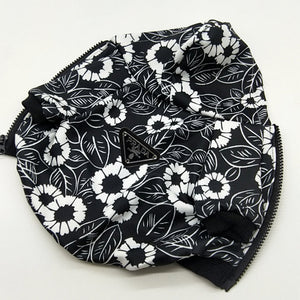 Close-up black floral print dog hoodie showing Pawda triangle logo and pocket detail