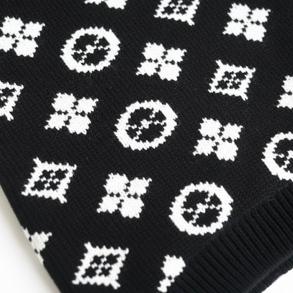 Close-up detail of white monogram pattern on black knit dog sweater fabric