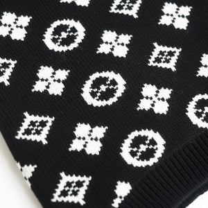Close-up detail of white monogram pattern on black knit dog sweater fabric