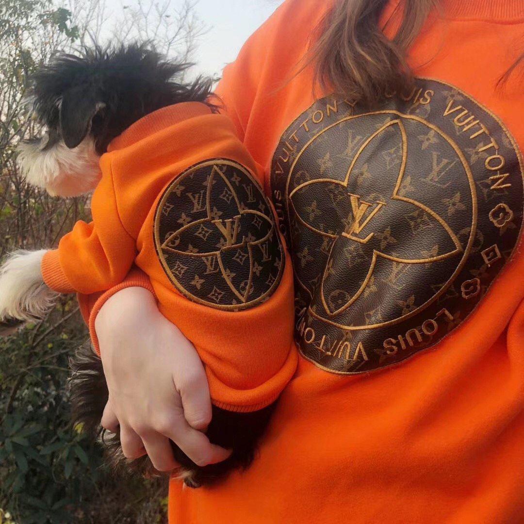 Orange dog sweatshirt on small white and black dog showing monogram patch detail
