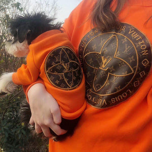 Orange dog sweatshirt on small white and black dog showing monogram patch detail