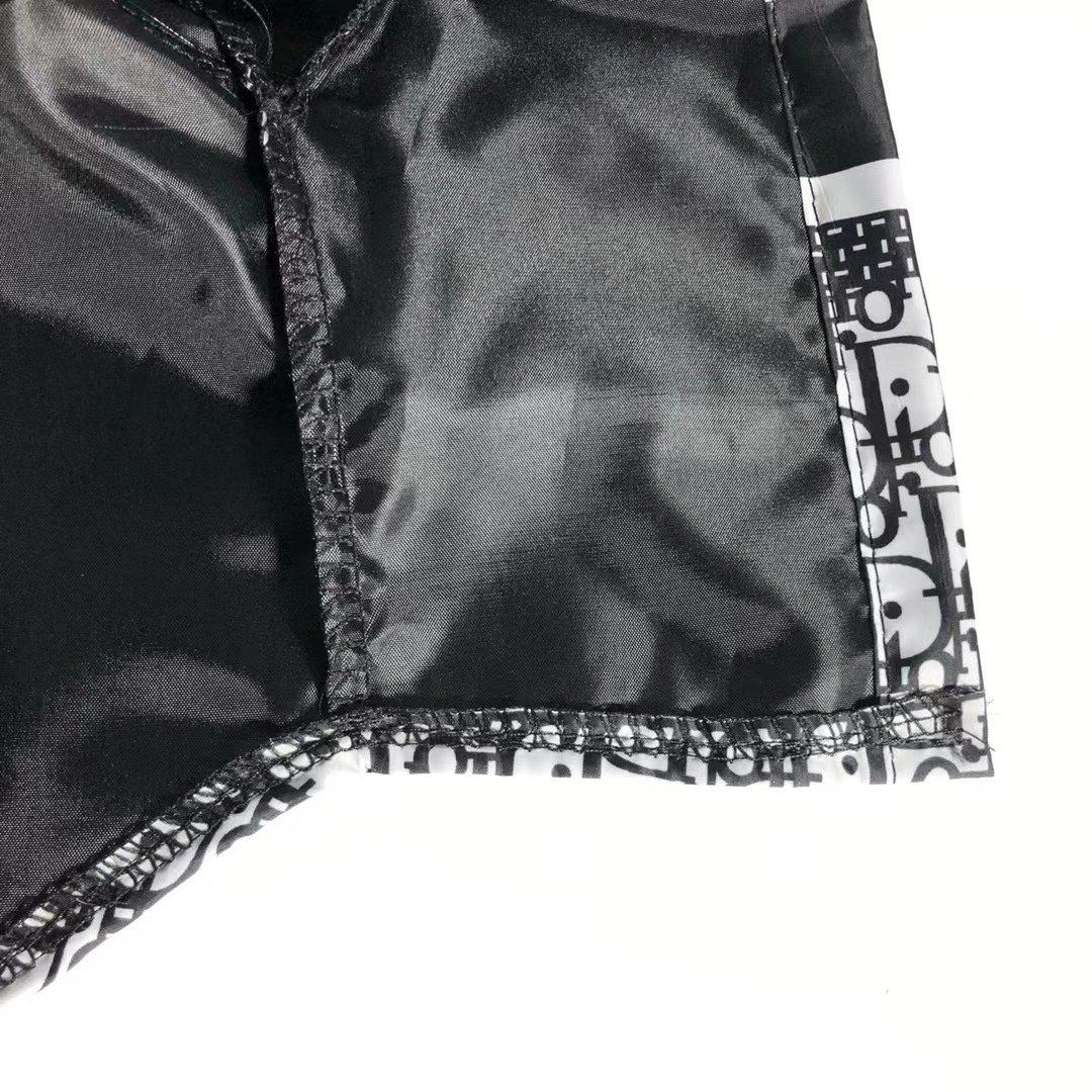 Close-up detail of black nylon construction and oblique print pattern on windbreaker