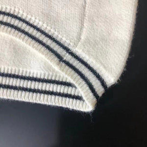 Close-up of ribbed knit hem detail with black stripe trim on cream dog sweater