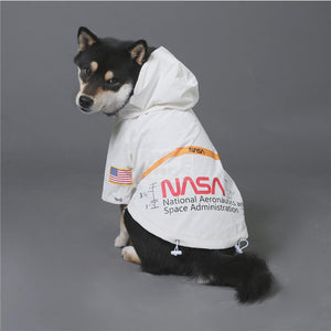 Black and tan dog wearing white NASA windbreaker with reflective stripe