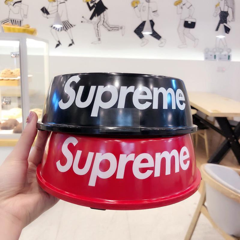 Red dog bowl with white Supreme branding being held in hand